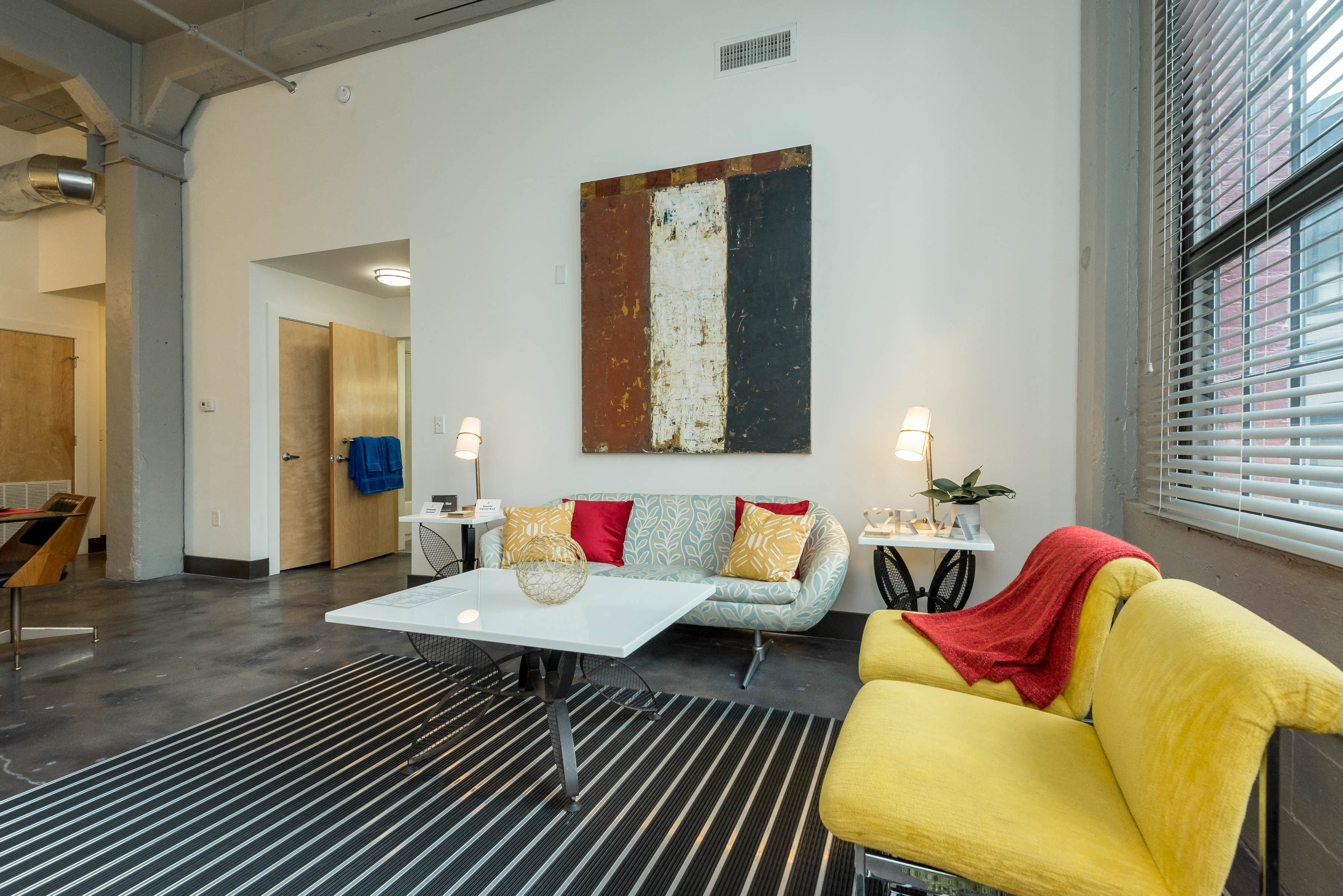A living room with a yellow couch and a white coffee table.