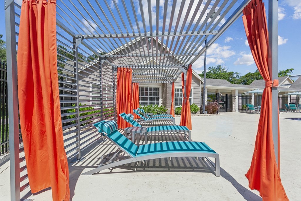 a row of lounge chairs under a metal structure with orange curtains  at Palm Crossing, Winter Garden, Florida
