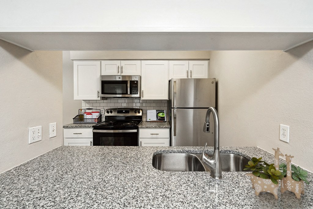 a kitchen with granite counter tops and stainless steel appliances at The Reserve At Barry Apartments, Kansas City