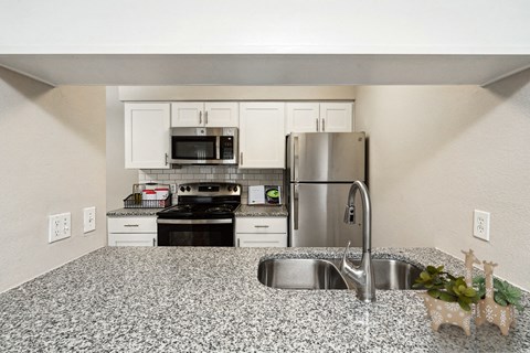 a kitchen with granite counter tops and a stainless steel refrigerator