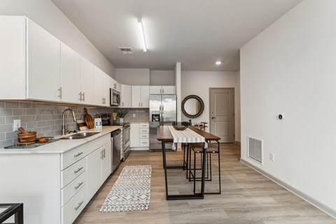 an open kitchen and dining room with white cabinets and a wooden floor