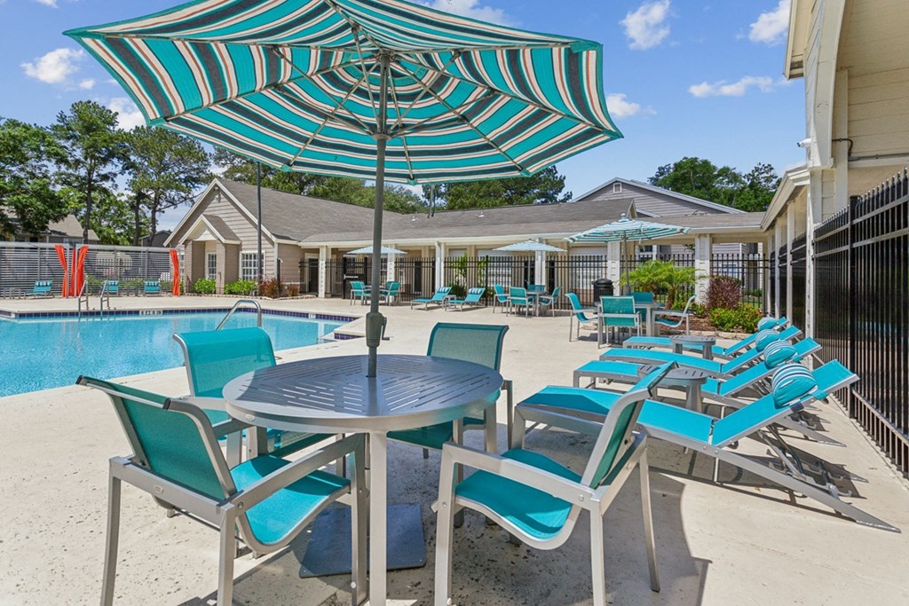 our apartments have a pool and patio with chairs and umbrellas  at Palm Crossing, Winter Garden, Florida