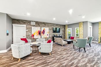 A living room with a grey sofa, red chair, and a painting on the wall at Proximity Apartments, Charleston, SC