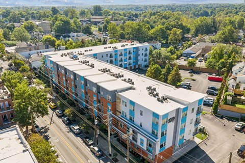 A multi-story building with a blue and white exterior is surrounded by trees and a parking lot.