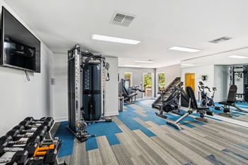 A gym with a variety of equipment including treadmills, weights, and exercise machines.