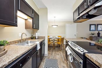 a kitchen with granite counter tops and a stainless steel sink at The Grove at Lyndon, Louisville