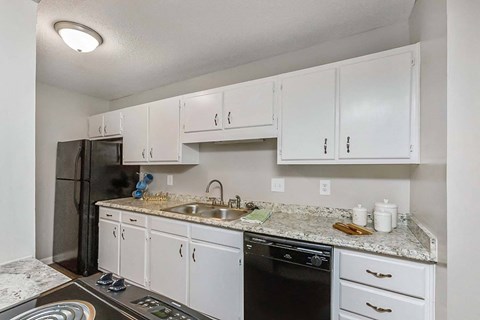 A kitchen with white cabinets and granite countertops.