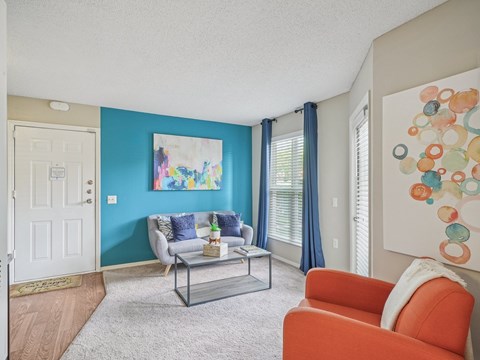 A living room with a blue wall and a painting on it.