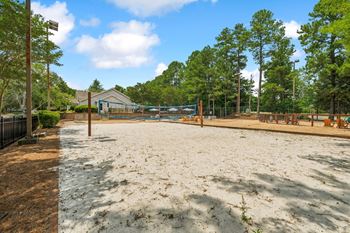 A sandy area with trees and a building in the background.
