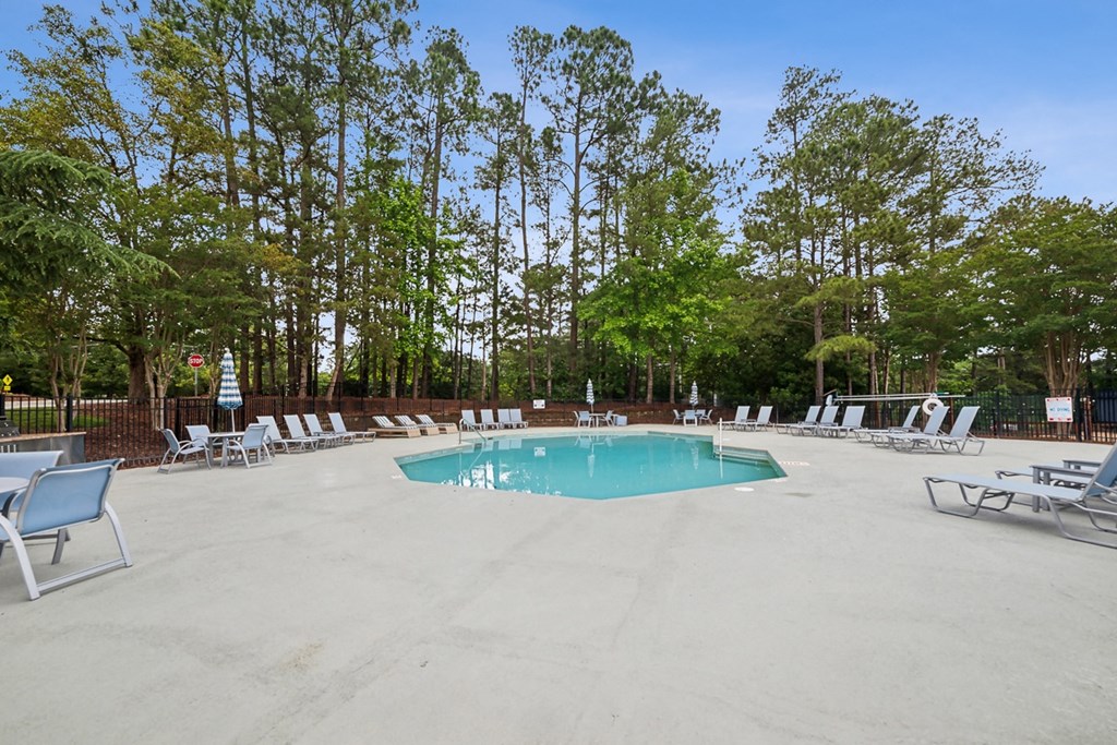 our resort style pool is surrounded by chairs and trees