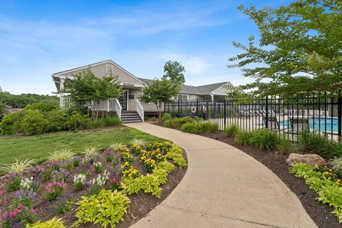 a sidewalk in front of a house with a pool