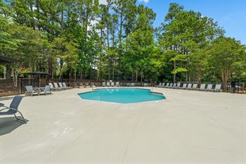 A large swimming pool surrounded by trees and lounge chairs.