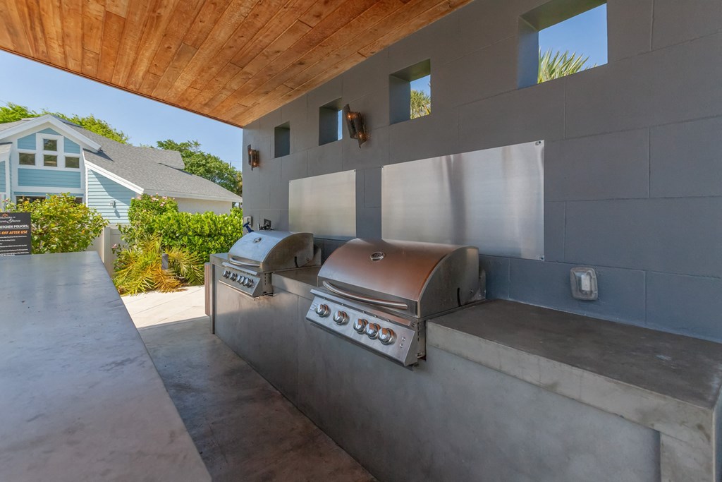 an outdoor kitchen with a grill and a wooden ceiling