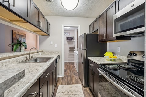 A kitchen with black appliances and a marble countertop. at The Timbers Apartments, Richmond 23235