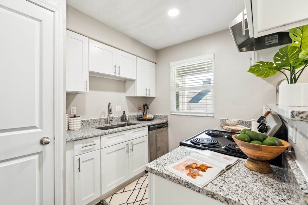 A kitchen with white cabinets and granite countertops. at Woodcreek Apartments, Cary