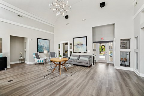 A living room with a grey couch, a wooden table and chairs, and a chandelier.