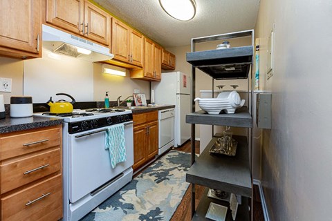 A kitchen with a white stove and wooden cabinets.