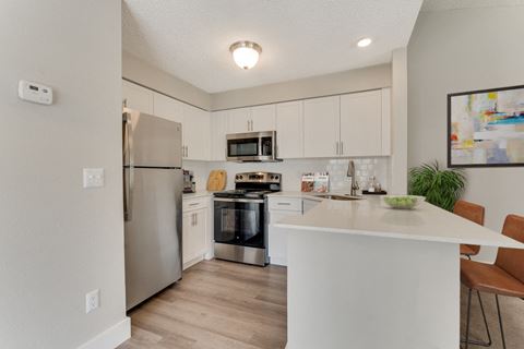 a kitchen with white cabinetry and stainless steel appliances at Palm Crossing Apartments in Winter Garden, FL