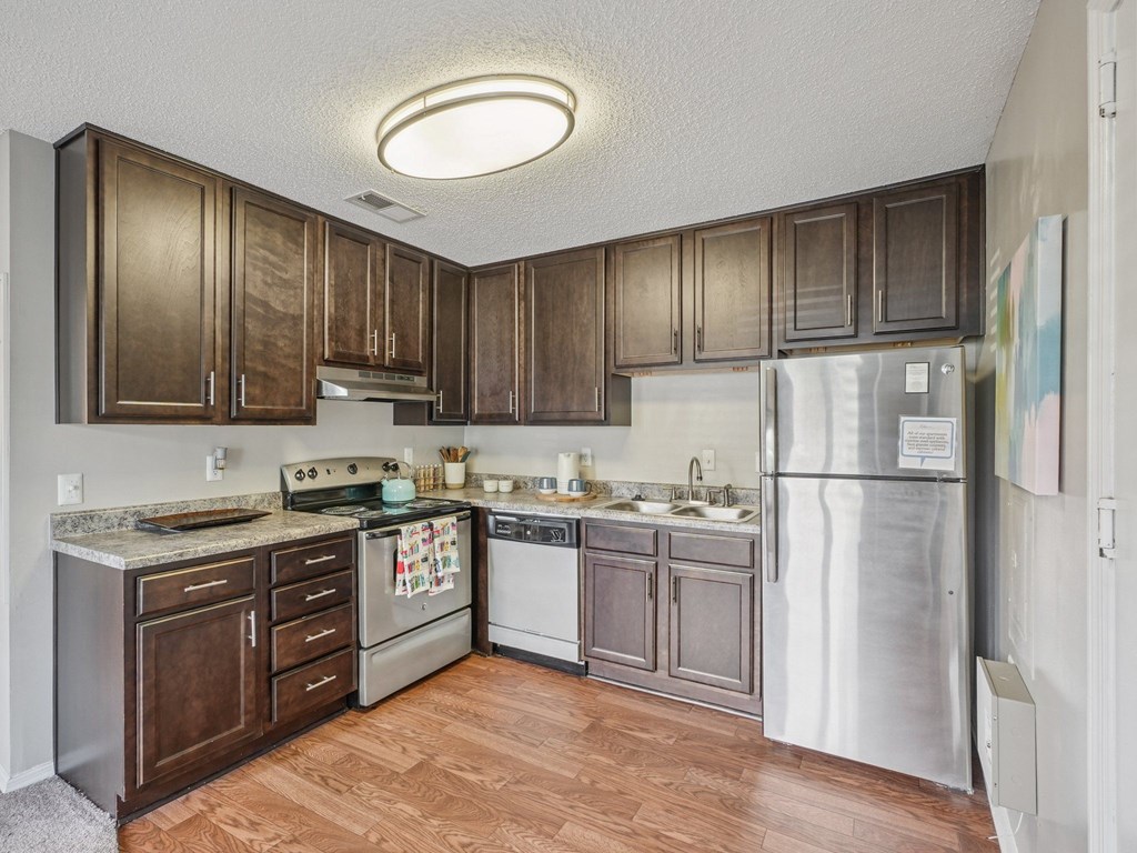 A kitchen with wooden cabinets and a refrigerator at The Falls Apartments in Raleigh NC