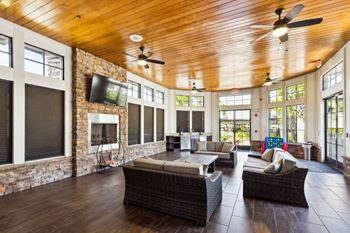 a living room with wicker furniture and a stone fireplace at The Loree, Jacksonville, 32256
