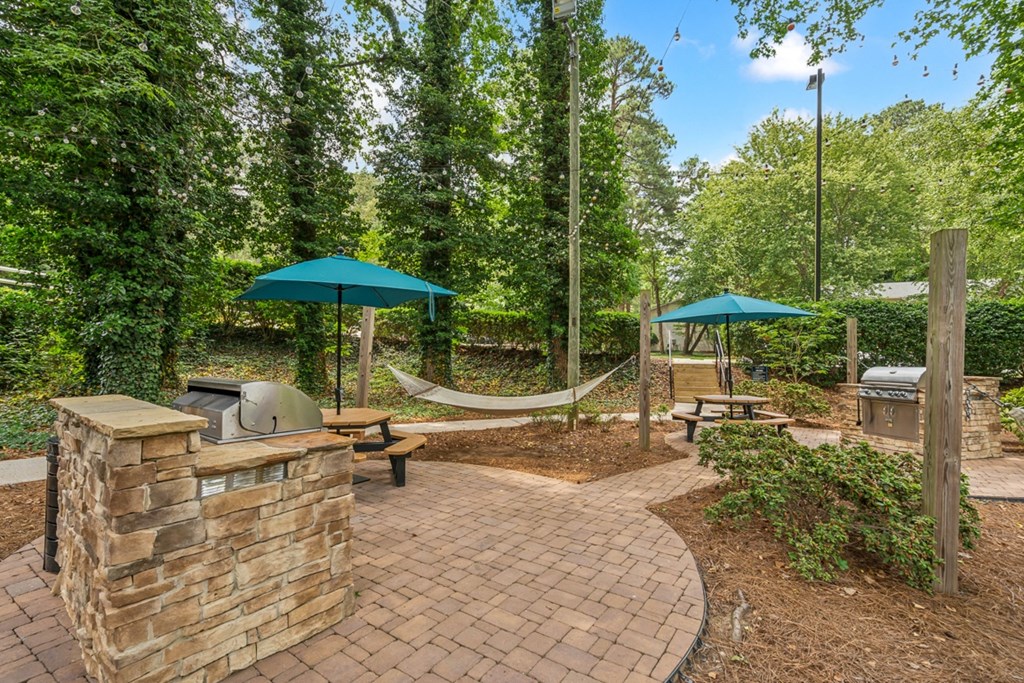 a brick patio with hammocks and umbrellas