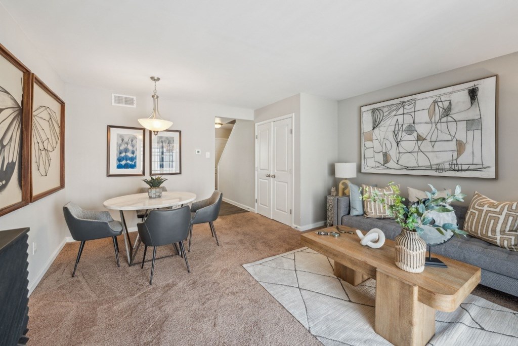 A living room with a grey couch, a white table, and a painting on the wall at Staples Mill Townhomes Apartments, Richmond, Virginia