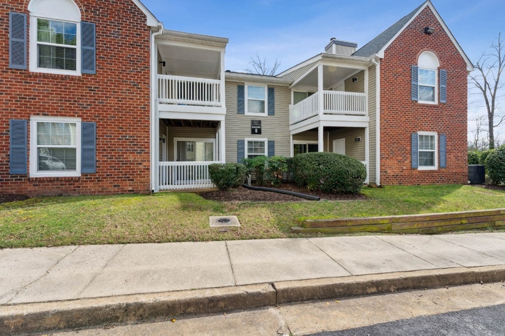 the view of an apartment building with a sidewalk in front of it