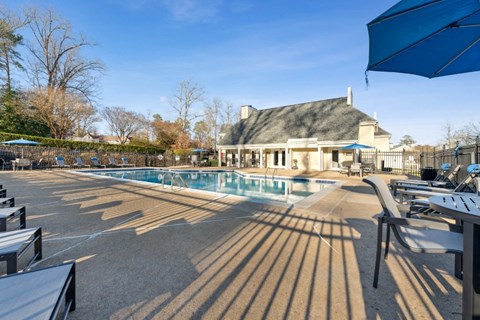 a swimming pool with chairs and umbrellas in front of a house at Ashton Creek, Chester