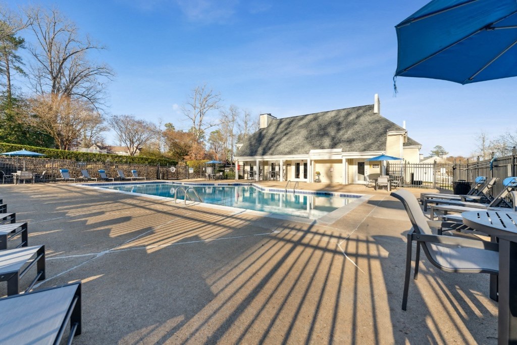 a swimming pool with chairs and umbrellas in front of a house a swimming pool with chairs and umbrellas in front of a house at Ashton Creek, Chester