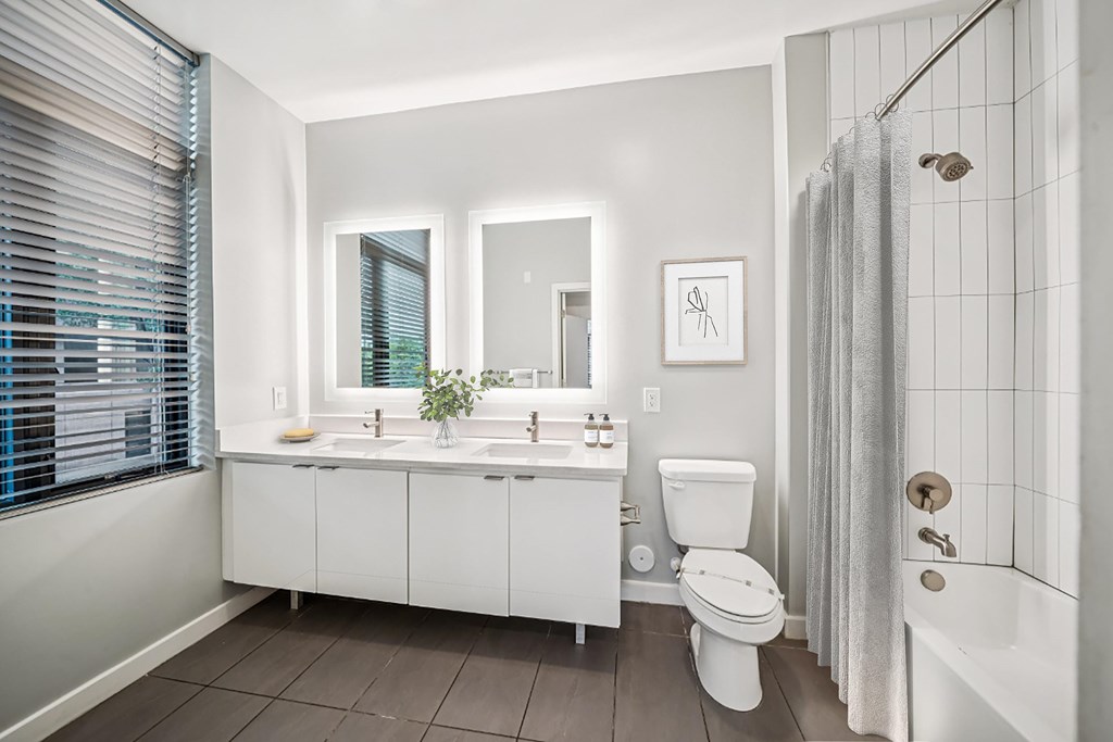 A white bathroom with a toilet, sink, and shower.