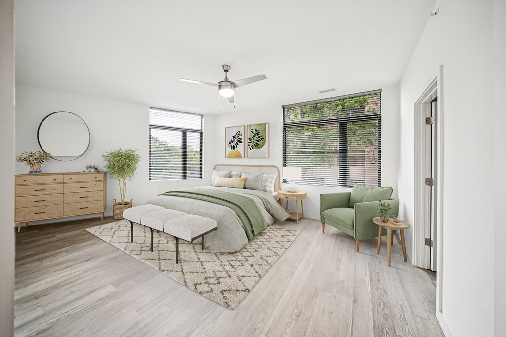 A bedroom with a bed, chair, and a plant.
