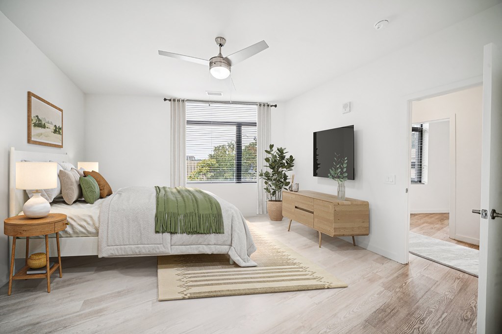 A bedroom with a bed, a side table, a dresser, and a ceiling fan.