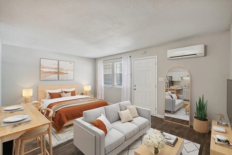 A well-lit bedroom with a bed, couch, and a dining table.