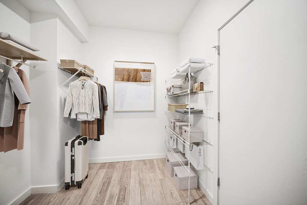 A walk in closet with clothes and a suitcase.