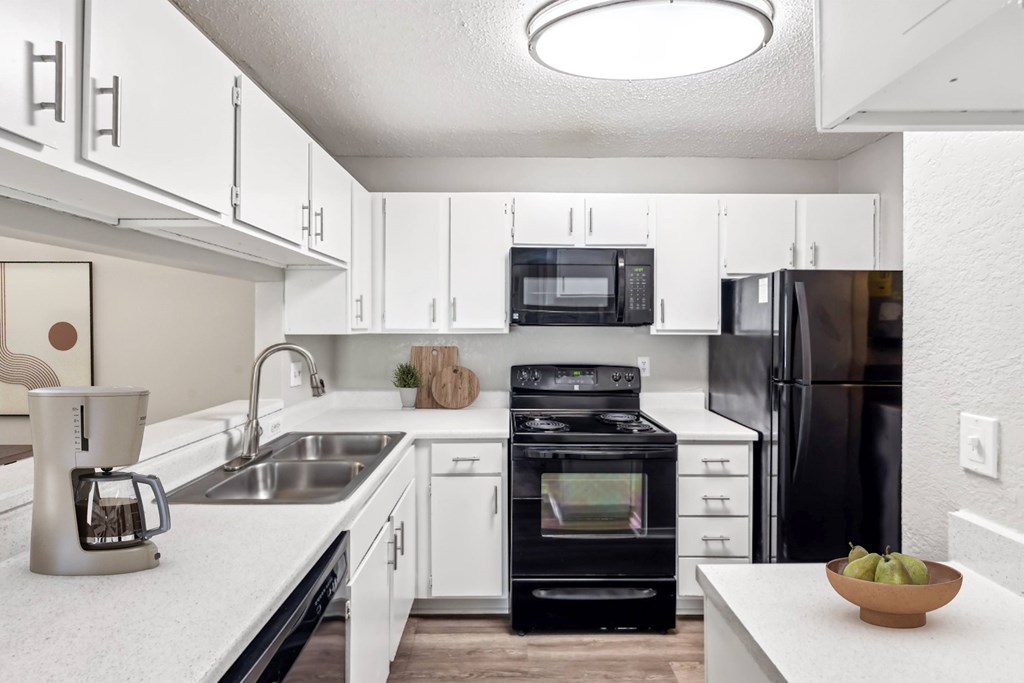 A modern kitchen with white cabinets and black appliances.at Chapel View, Chapel Hill, NC