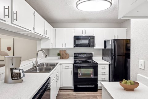 A modern kitchen with white cabinets and black appliances.