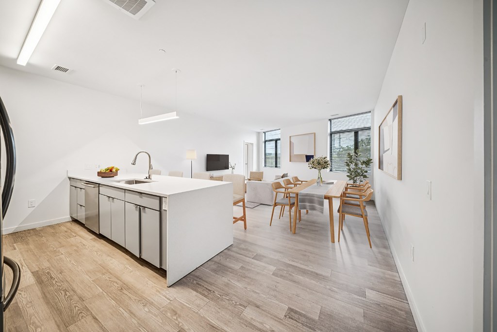 A kitchen with a white counter and wooden chairs.