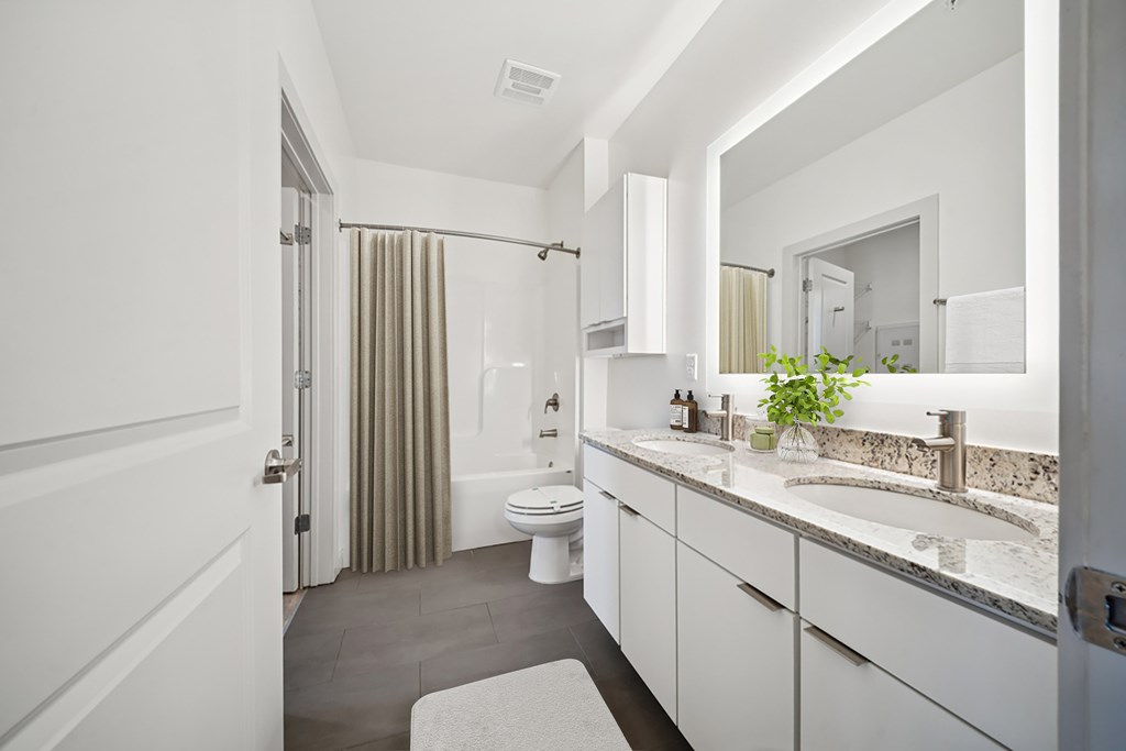 A bathroom with a toilet, sink, and mirror.