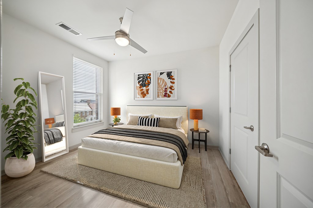 A bedroom with a bed, a ceiling fan, and a potted plant.