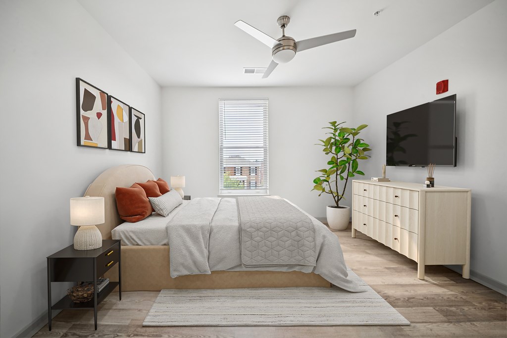 A bedroom with a bed, a ceiling fan, and a television.