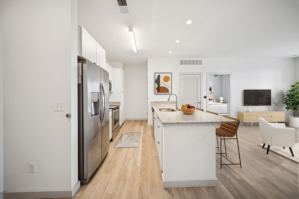 A modern kitchen with white appliances and a wooden floor.