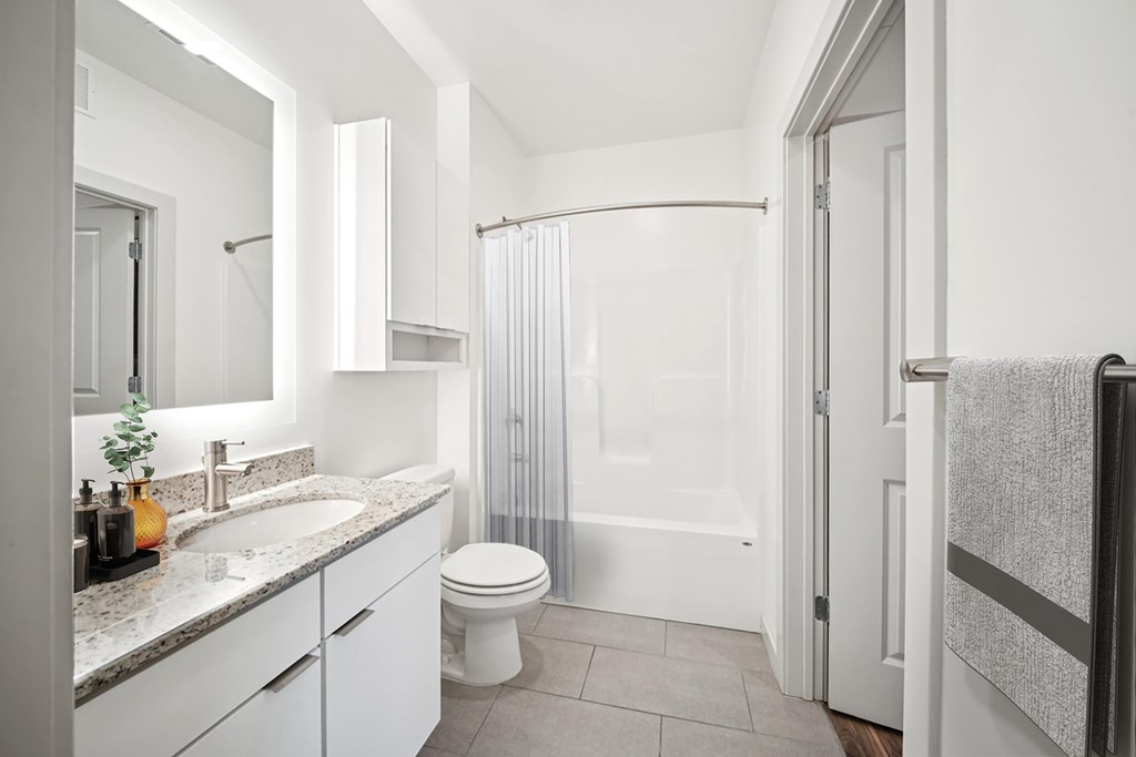 A white bathroom with a toilet, sink, and shower.