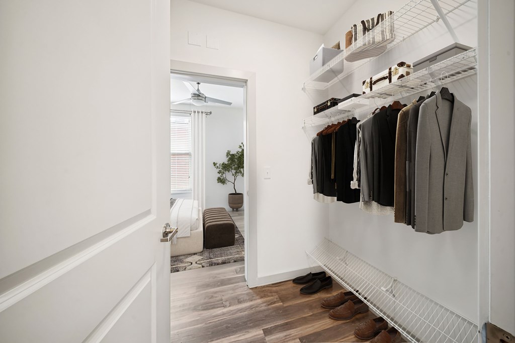 A hallway with a white door and a row of hanging coats.