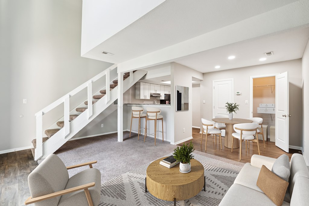 A living room with a staircase and a dining area at Woodcreek Apartments, Cary, 27511