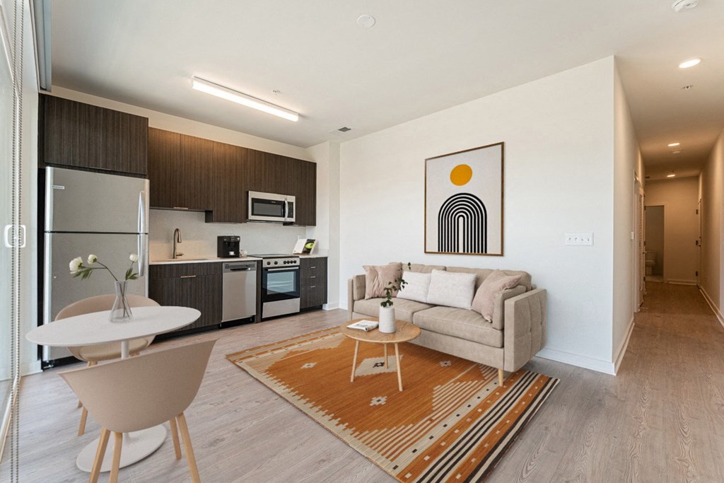 a living area with a couch table and chair and a kitchen with a stove microwave and sink