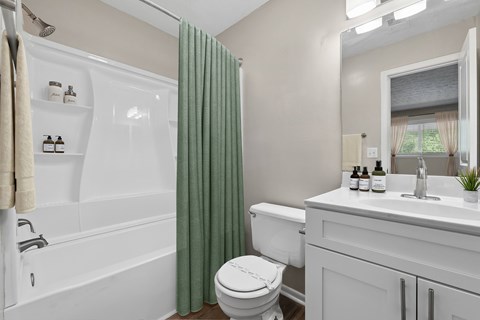 A white bathroom with a toilet, sink, and shower.