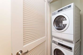A white washing machine is stacked on top of another in a small laundry room at Circ Apartments, Richmond, Virginia