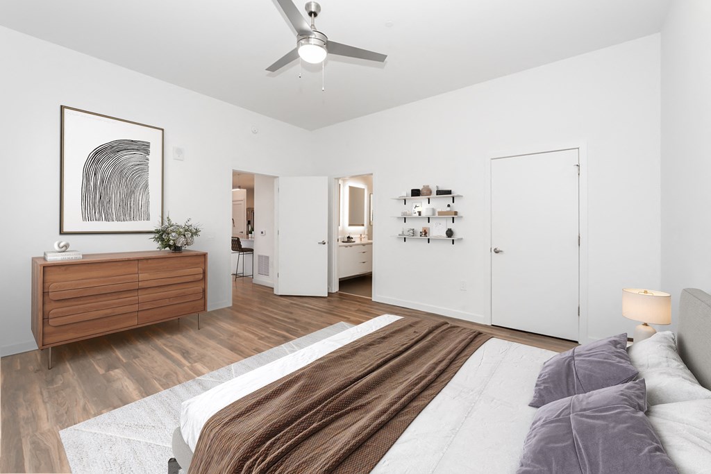 A bedroom with a bed, dresser, and a painting on the wall.