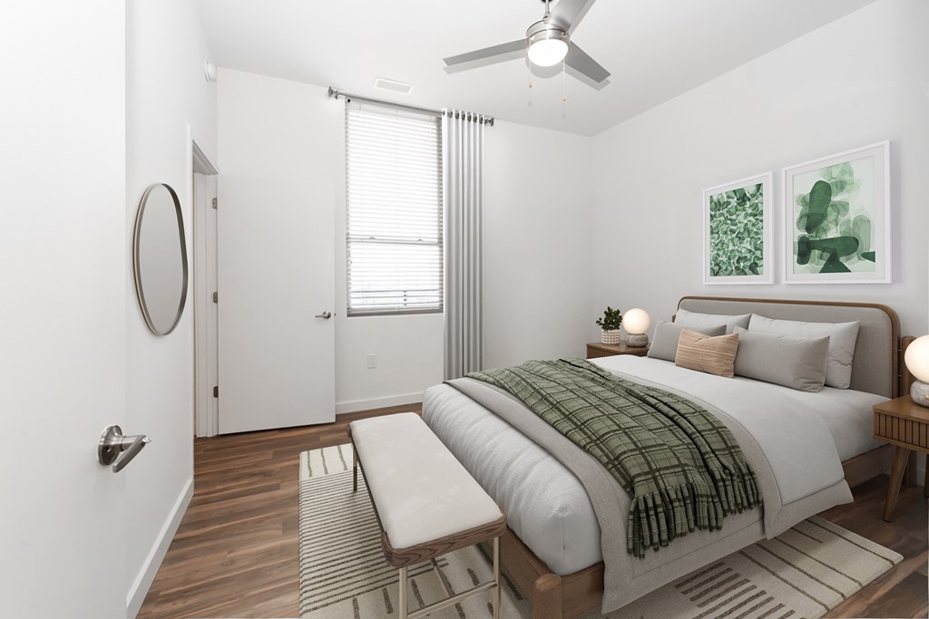A bedroom with a bed, a bench, and a ceiling fan.