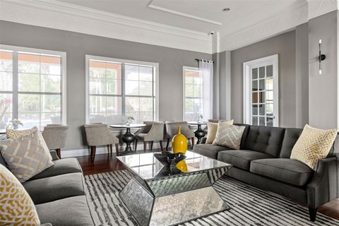 A living room with grey couches and yellow pillows.